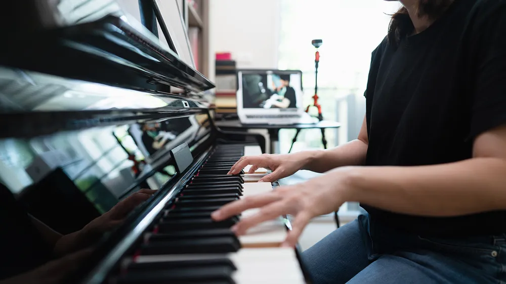 An adult student playing piano at home